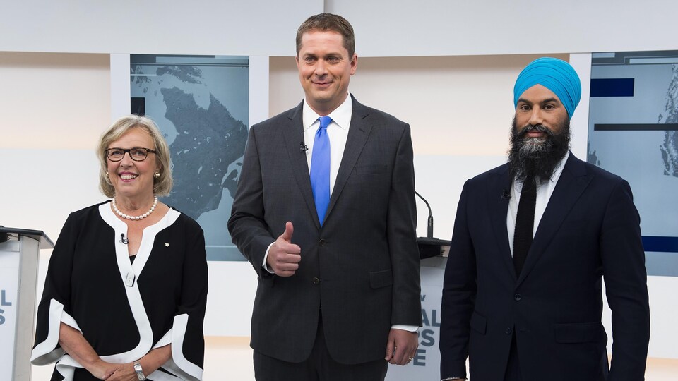 Elizabeth May, Andrew Scheer et Jagmeet Singh sourient à la caméra avant le débat.