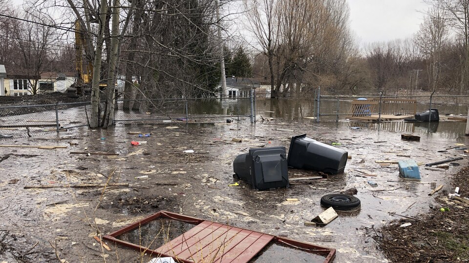 De nombreux débris jonchent une rue dans laquielle il reste un peu d'eau.