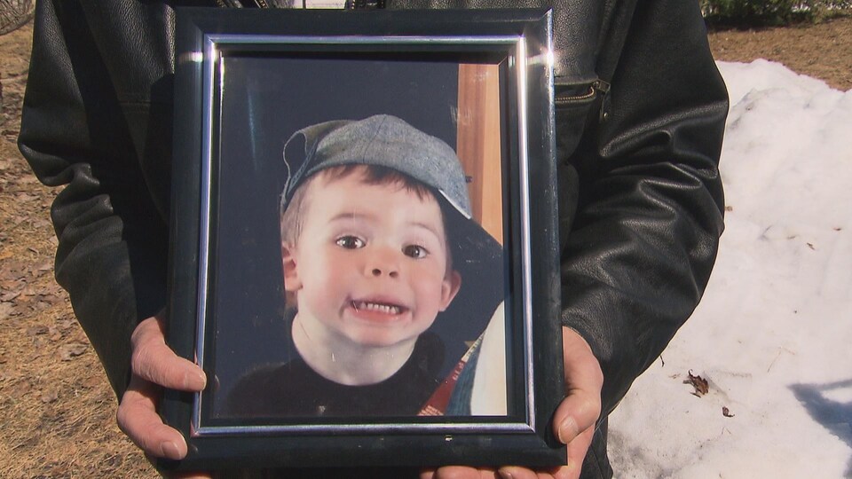 Un grand-père tenant la photo de son petit-fils entre ses mains.