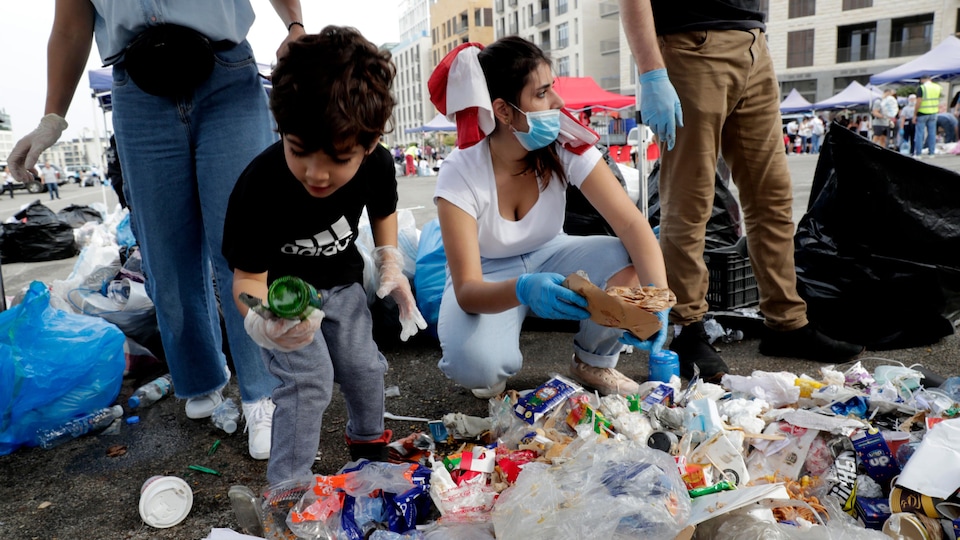 Un enfant ramassant une bouteille jetée par terre.