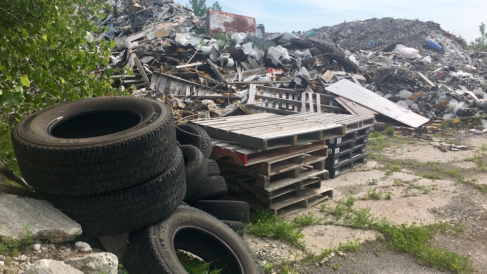 Un monticule de déchets à côté de palettes de bois et de pneus.