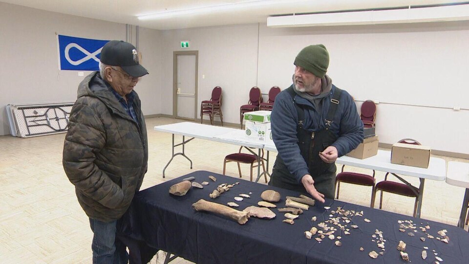 Deux personnes devant des os sur une table.