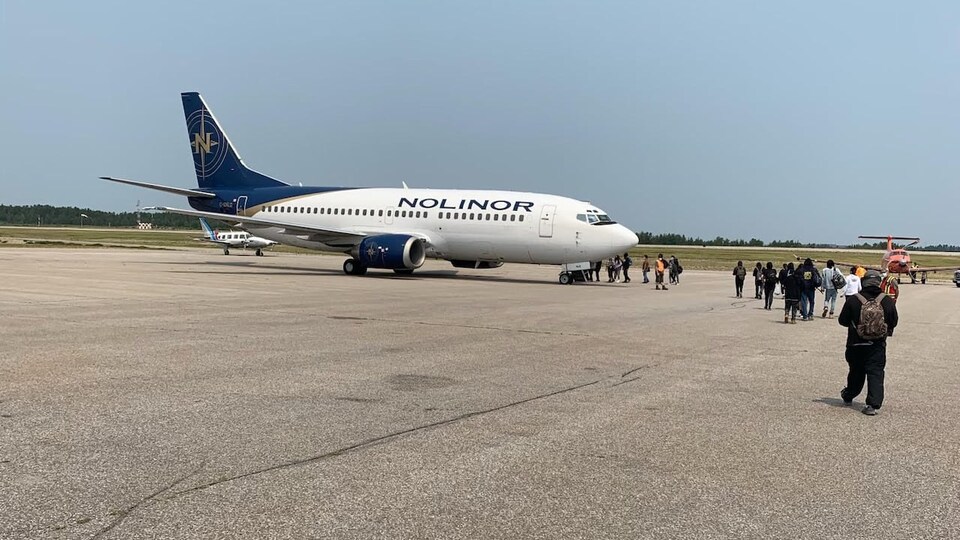 Des résidents marchent sur le tarmac vers un avion.