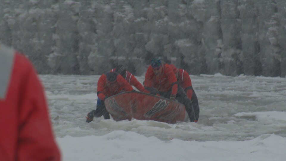 Des canoéistes en action sur les glaces du fleuve Saint-Laurent, sous la neige.