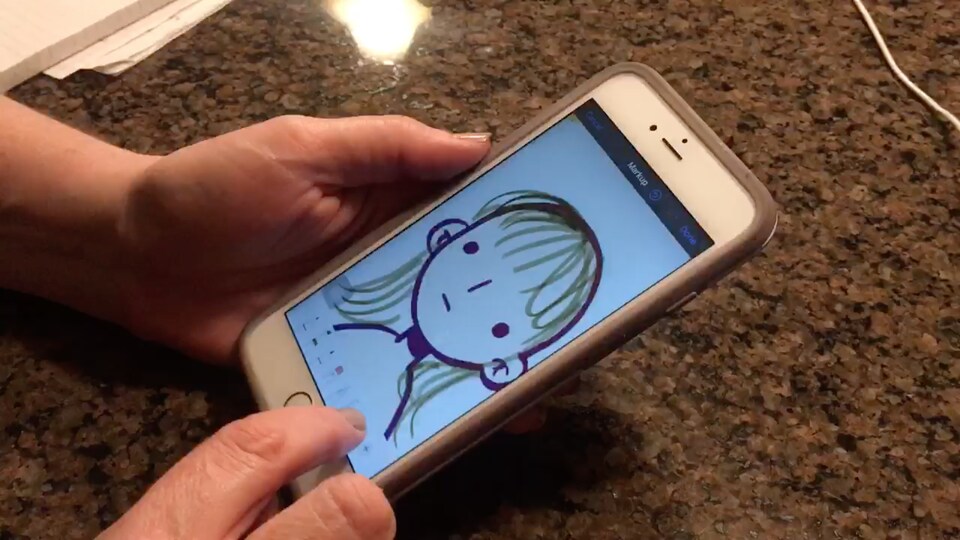 Une femme desssine son auto-portrait sur un téléphone
