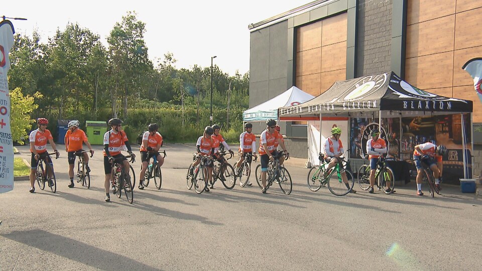 Un groupe d'une vingtaine de cyclistes à vélo sont prêts à partir sur une ligne de départ.