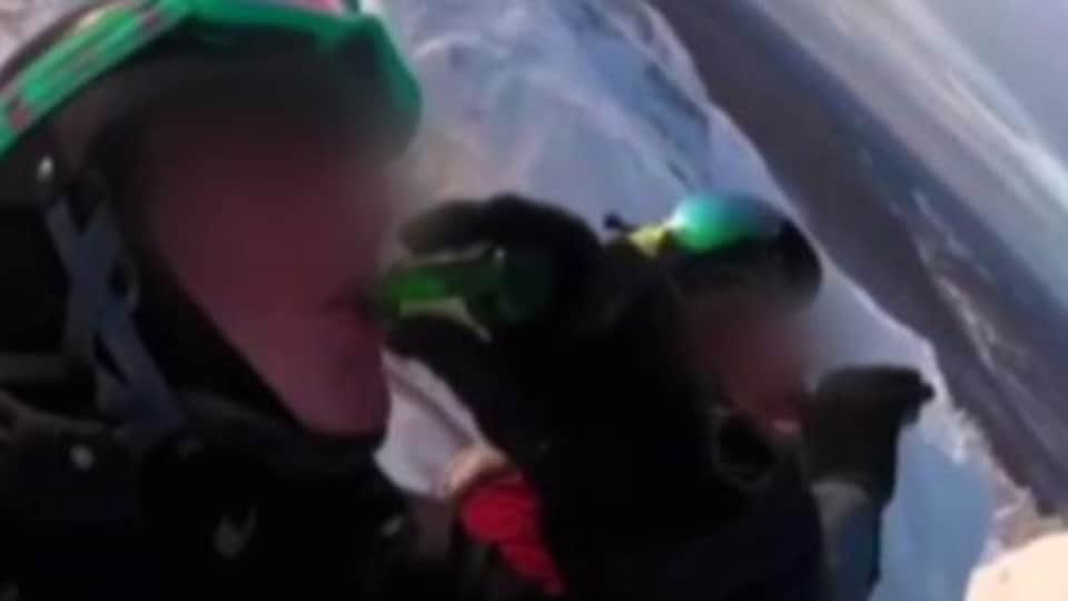 Deux skieurs en haut d'une pente calent une mini-bouteille de spiritueux.