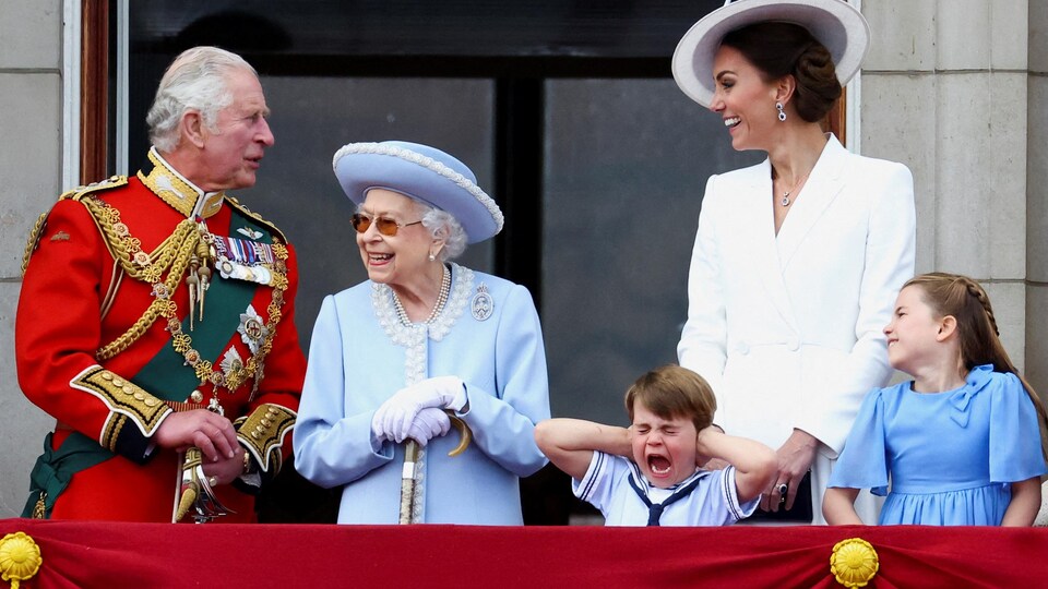 Photographié sur le balcon de Buckingham aux côtés de son grand-père, le prince Charles, de son arrière-grand-mère, la reine Élisabeth, de sa mère Catherine et de sa grande sœur Charlotte, le prince Louis se bouche les deux oreilles. 