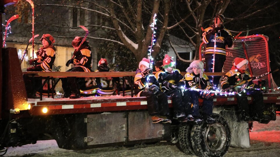 Des enfants habillés en costume de hockey sur un char allégorique illuminé.