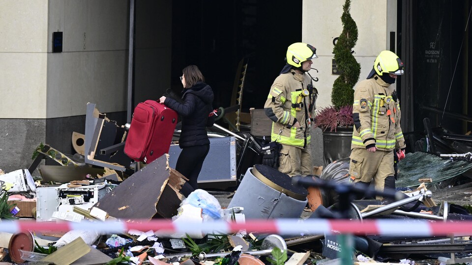 Firefighters survey the damage on the street in front of the hotel.