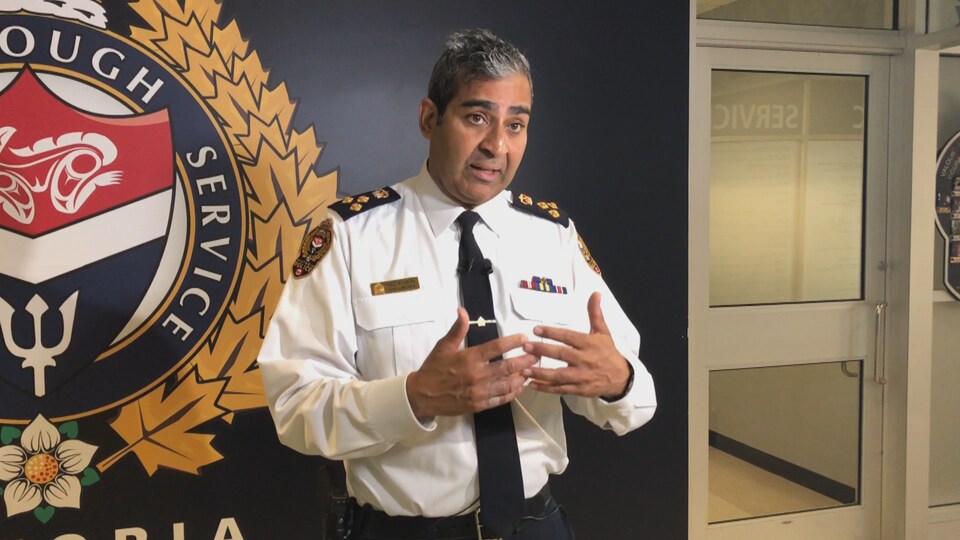 Le chef de la police, en uniforme, tient une conférence de presse dans l'entrée du commissariat.