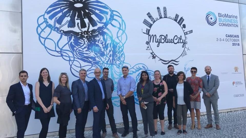 La délégation du Québec devant l'affiche qui fait la promotion de l'édition portugaise de la convention BioMarine