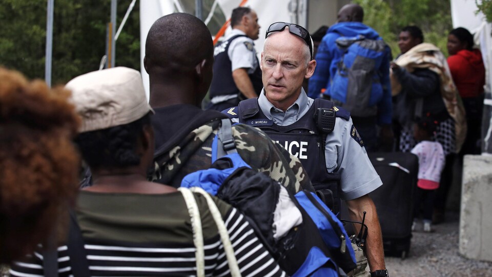Un employé de la Gendarmerie royale du Canada (GRC) accueille des demandeurs d'asile à la frontière canado-américaine à Saint-Bernard-de-Lacolle.