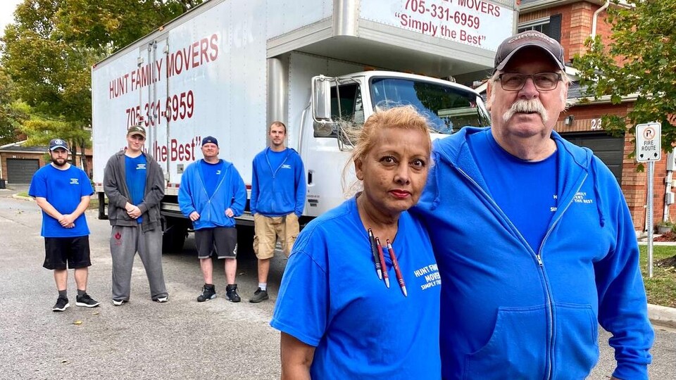 Karina Shaak, Frank Hunt et des employés devant un camion de déménagement.