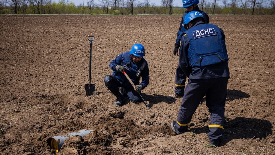 Des membres d'une équipe de déminage à l’œuvre pour détruire un missile non explosé en Ukraine.