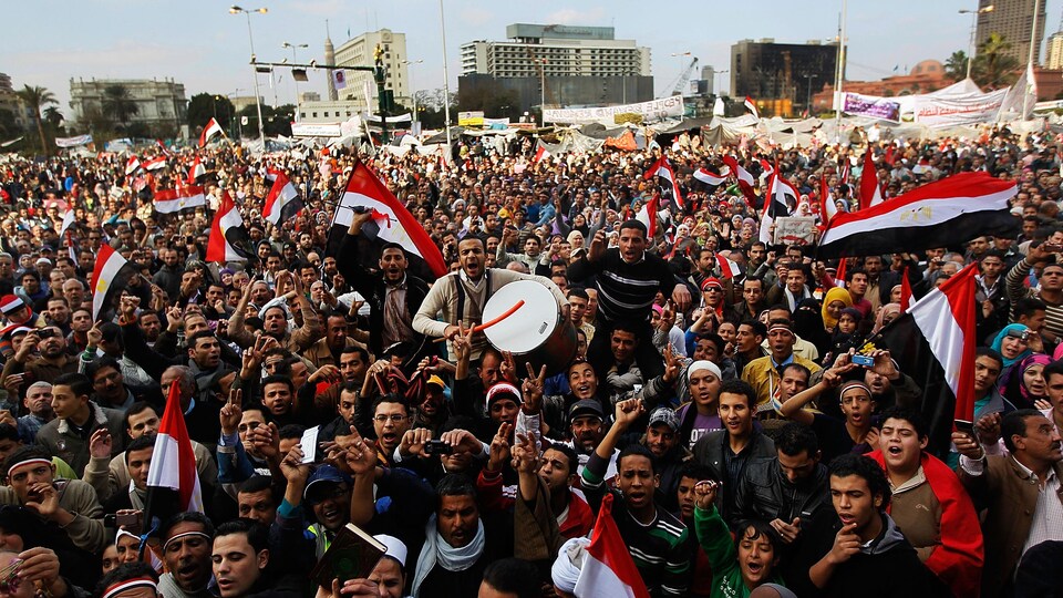 Des centaines de personnes, dont plusieurs brandissant des drapeaux égyptiens, manifestent leur joie dans une rue du Caire.