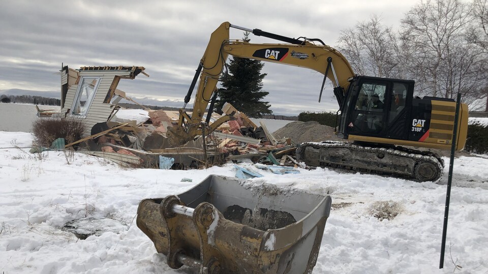 Une pelle mécanique détruit une résidence sur la rive du lac Saint-Jean.