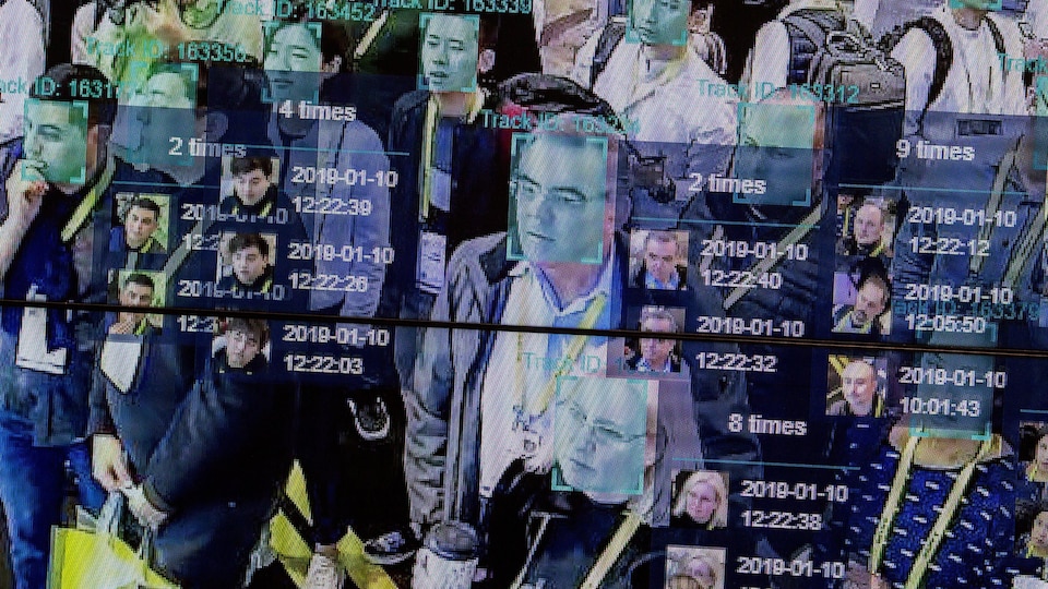 Plusieurs personnes apparaissent sur un écran, le visage encadré par un logiciel de reconnaissance faciale.