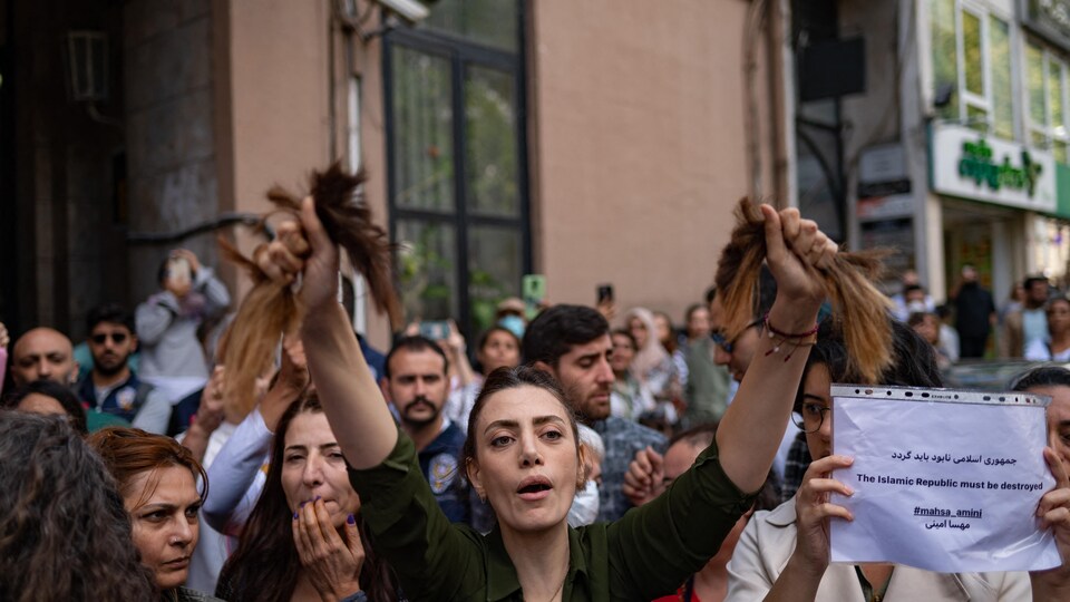 Une Iranienne vivant en Turquie brandit ses cheveux après les avoir coupés avec une paire de ciseaux.