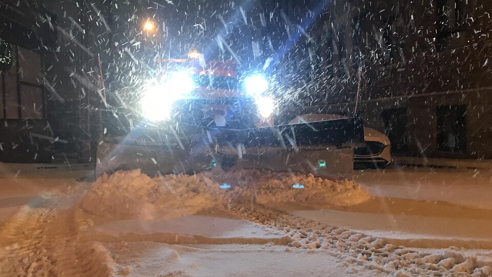Une déneigeuse de face avec les phares allumées