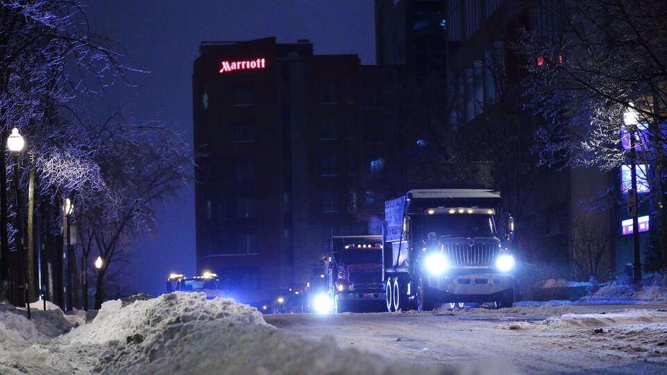 Des camions en attente d'être chargés de la neige accumulée dans les rues.