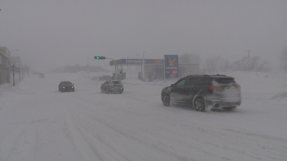 Des voitures roulent dans une tempête de neige.