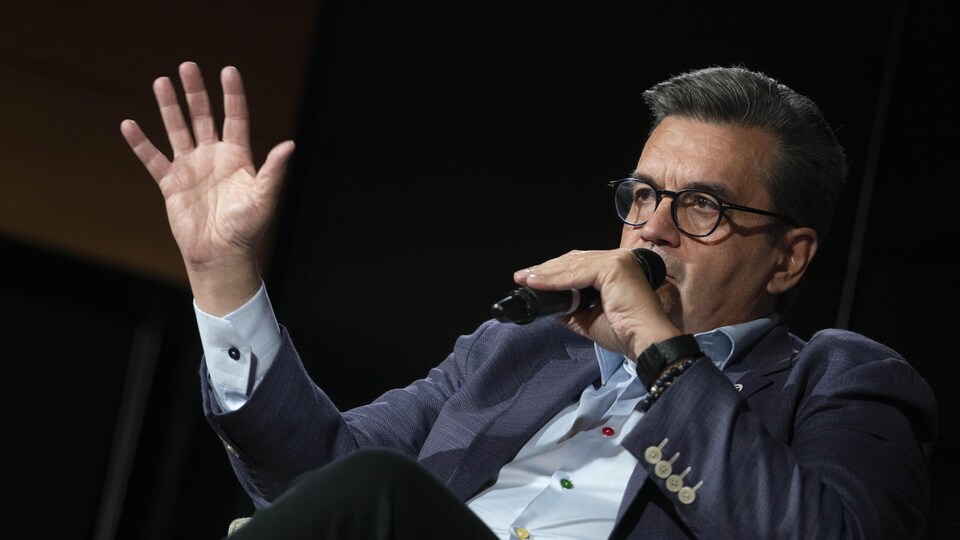 Assis, Denis Coderre parle dans un micro.