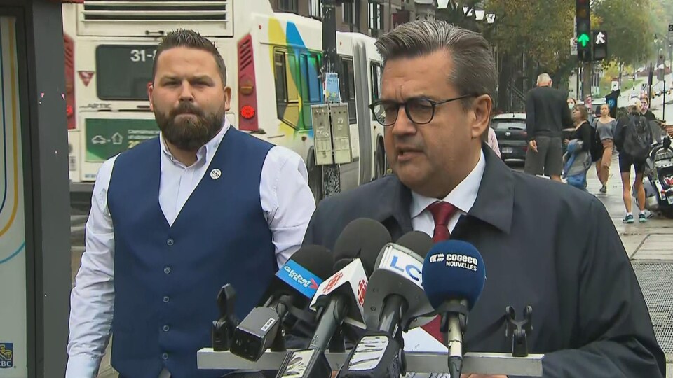 Dans une rue, Denis Coderre devant des micros, avec Benoit Langevin derrière lui.