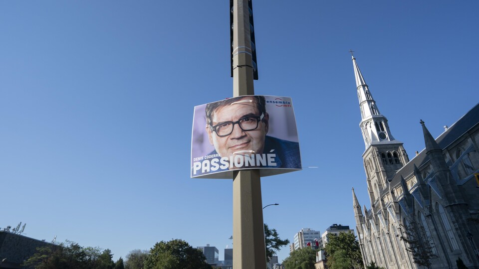 Le mot « passionné » écrit sur une pancarte avec un gros plan du visage de Denis Coderre.