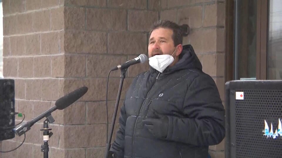 Le maire debout sur le perron d'un édifice, devant des micros, vêtu d'un manteau d'hiver.