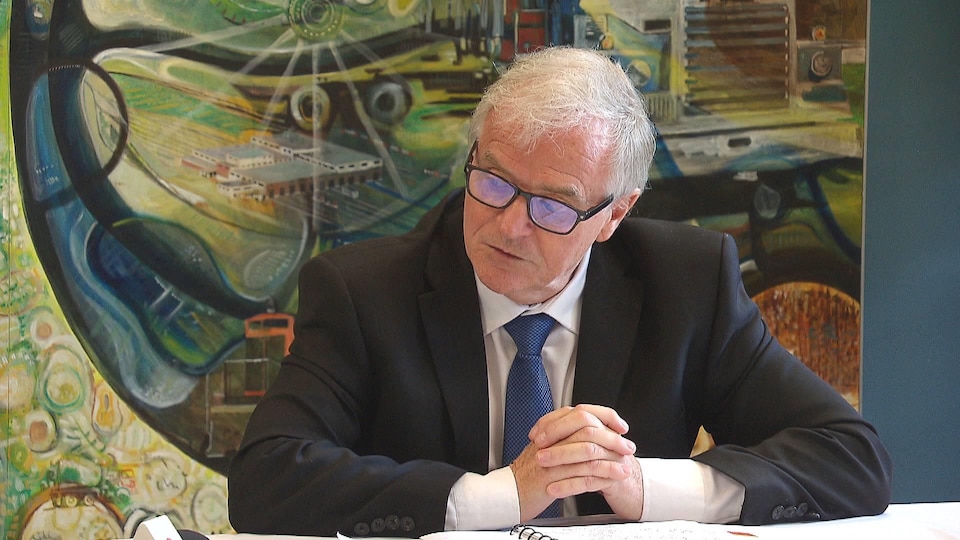 Denis Prud’homme assis devant des documents.