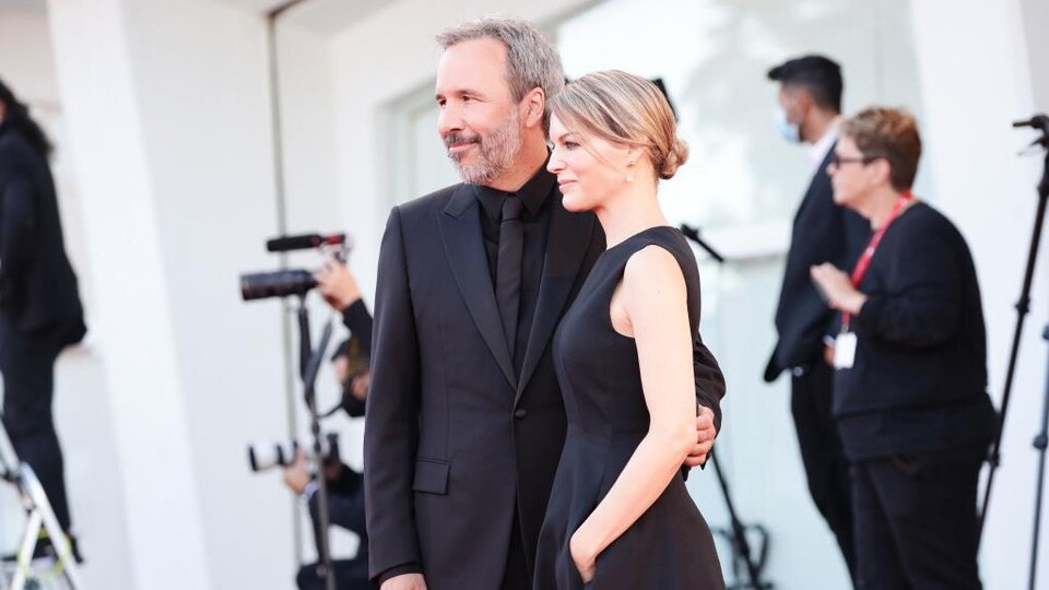 Une femme et un homme vêtus de noir posent pour les photographes.