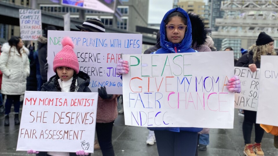 Deux fillettes tiennent des pancartes, entourées de manifestants.