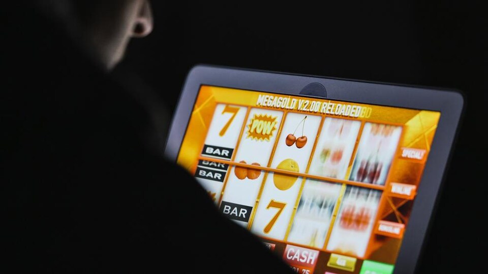 Un homme joue devant une machine à sous virtuelle sur un écran.