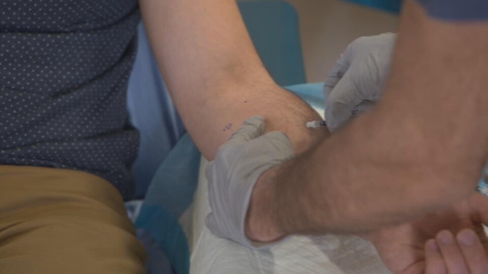 Un professionnel de la santé pique une seringue dans le bras d'un patient.