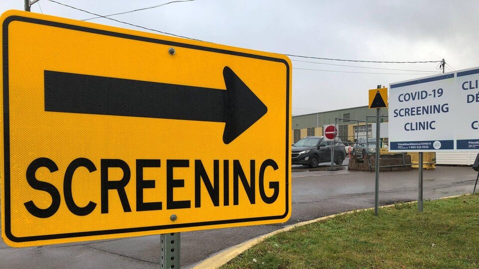 Une pancarte jaune sur laquelle le mot SCREENING est écrit, avec une flèche pointant vers un bâtiment.