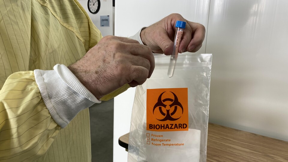 Un travailleur de la santé place une éprouvette dans un sac.