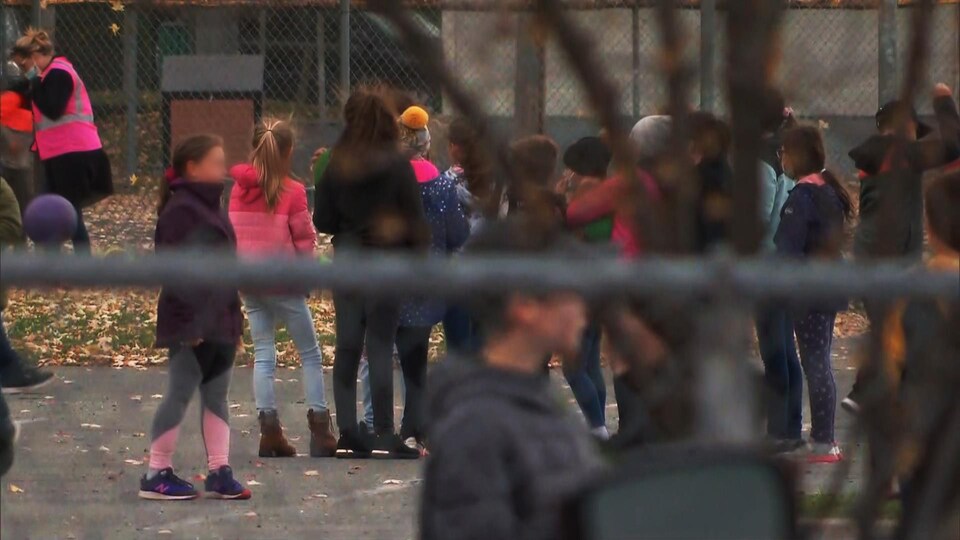 Des élèves dans une cour d’école en automne.
