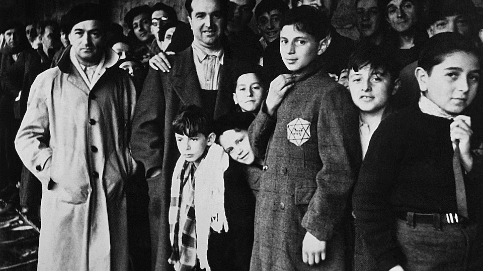 Sur cette photo de 1942, des hommes et des enfants regardent la caméra.