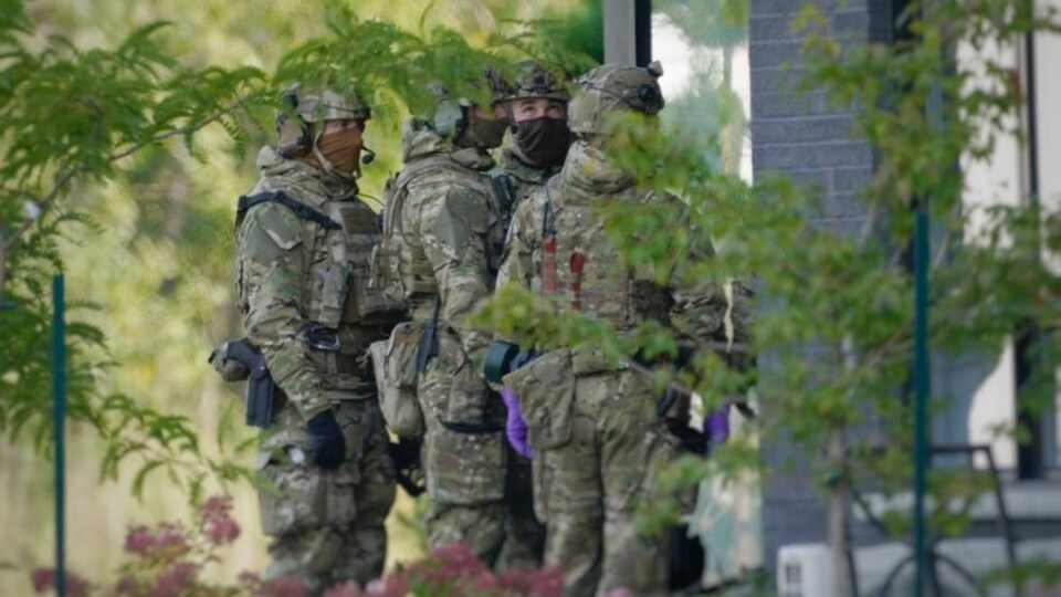 Des agents en tenue de camouflage transportent de l'équipement.