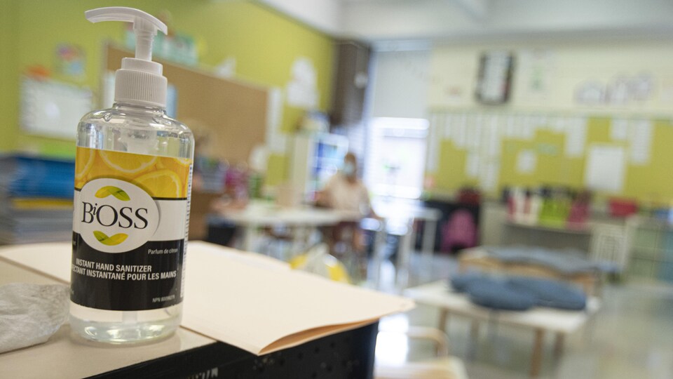 Une classe avec, en avant-plan, une bouteille de désinfectant.