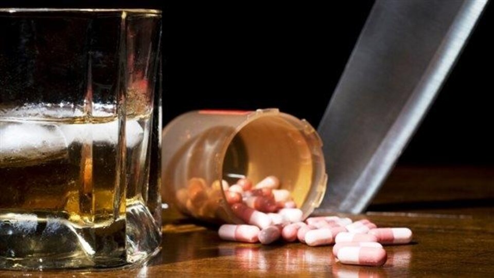 Un verre d'alcool et une bouteille de comprimés sur un bar