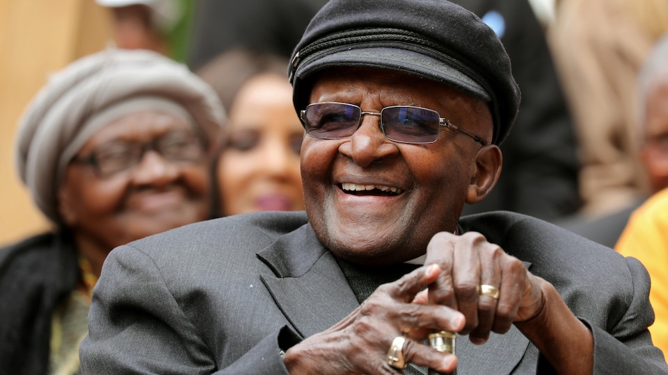 Une canne à la main, Desmond Tutu rit.