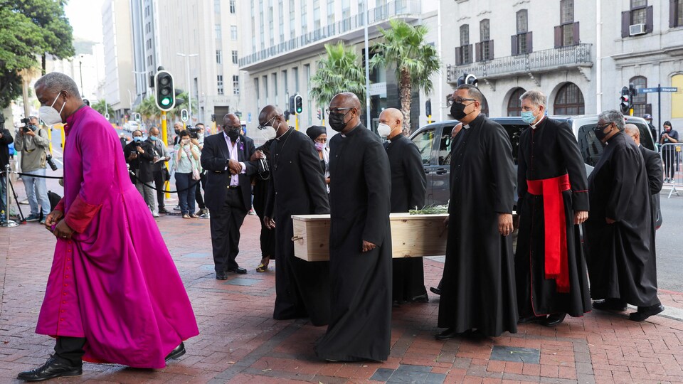 Un cercueil porté par plusieurs hommes en habits religieux.