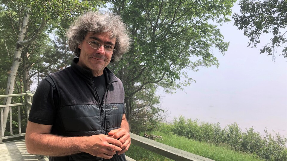 Le chercheur Robert Michaud, sur sa galerie à Bergeronnes, avec vue sur les eaux brumeuses du fleuve Saint-Laurent.