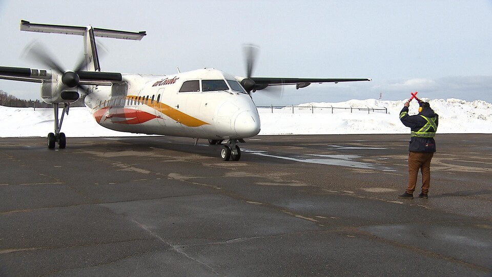 Les hélices d'un avion sont en marche, alors qu'un signaleur lui fait signe avant qu'il ne puisse décoller.