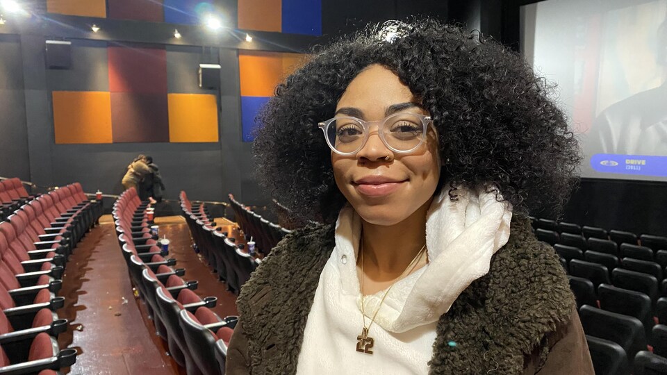 Destoni Willock sourit à la caméra dans une salle de cinéma.