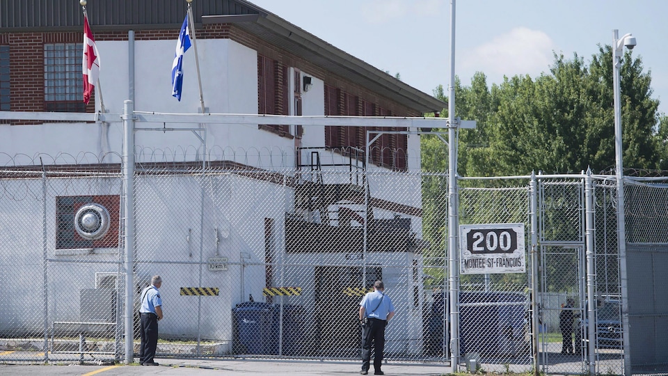 Des gardes se tiennent à l'extérieur des portes du centre de détention pour immigrants à Laval.