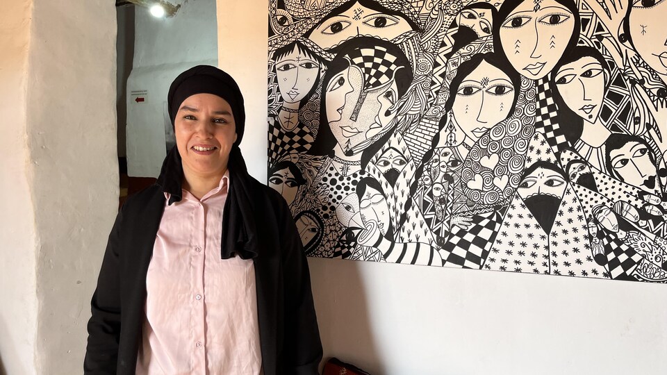 Hafida Zizi à côté d'un tableau représentant des femmes