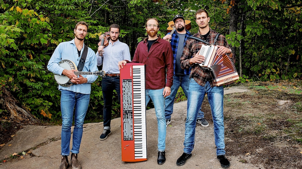 Un groupe de jeunes homme prend la pose dans la forêt avec leurs instruments.